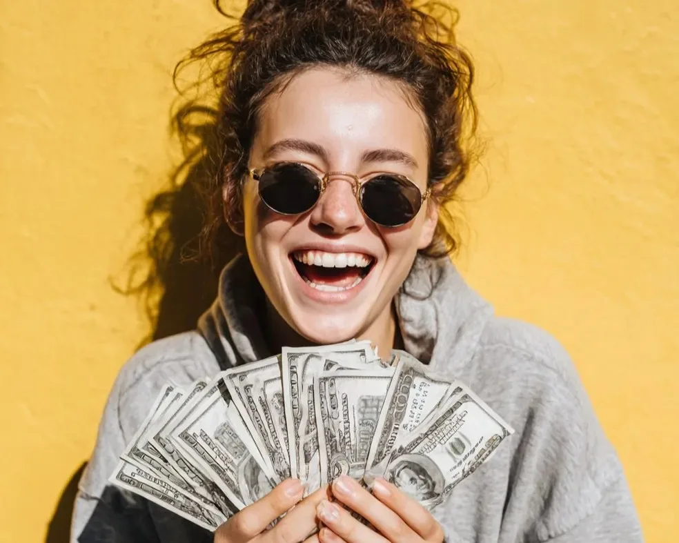 Happy woman holding cash — getting a same-day cash advance from Check n Go